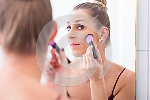 Woman powdering her face with cosmetic brush