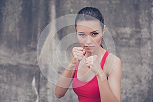 Woman power, self defence concept. Close up portrait of attractive serious fit boxer, ready for fight, on concrete wall