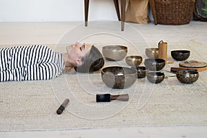 Woman practice meditation with tibetan singing bowls therapy: female meditating from sound massage