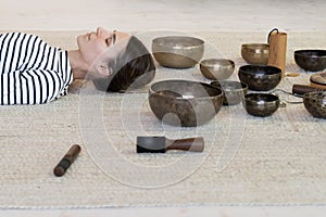 Woman practice meditation with tibetan singing bowls therapy: female meditating from sound massage