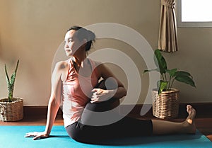 Woman practice yoga in dark room with morning sunlight.Ardha matsyendrasana