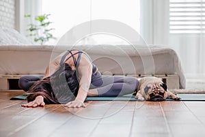 Woman practice yoga with dog pug breed