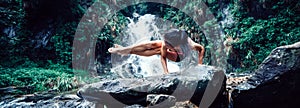 Woman practice yoga near waterfall in forest