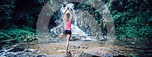 Woman practice yoga near waterfall in forest