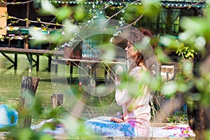 Woman practice yoga outdoor spring summer  day by the lake sit in lotus position with hands in anjali mudra