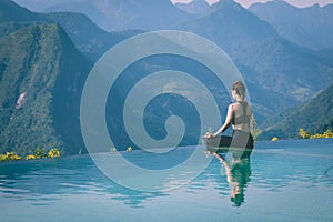 Woman practice yoga on the pool above the Mountain peak