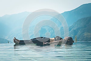 Woman practice yoga on the pool above the Mountain peak