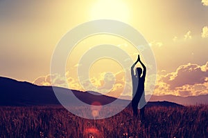 Woman practice yoga at sunset prairie