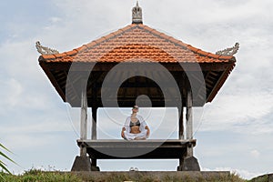 A woman practices meditation in a traditional Balinese pavilion, embodying tranquility and spiritual calm Meditative Sanctuary