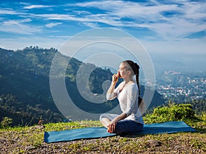 Woman practices pranayama in lotus pose outdoors photo