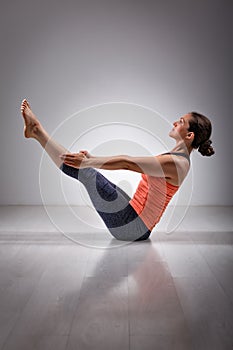 Woman practices yoga asana Paripurna navasana