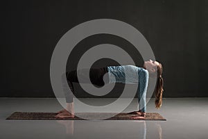 Woman practices yoga asana purvottanasana or upward facing plank