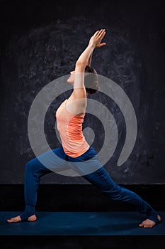 Woman practices yoga asana utthita Virabhadras