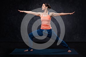 Woman practices yoga asana utthita Virabhadrasana