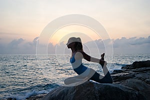 The woman practices yoga at dawn, there is an asana on a stone, dawn and an image of the girl, to enjoy dawn, to be happy with lif