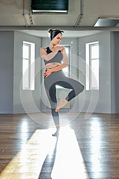 A woman practices yoga in a fitness room at dawn. Concentration, beautiful sunshine, stretching, healthy lifestyle.