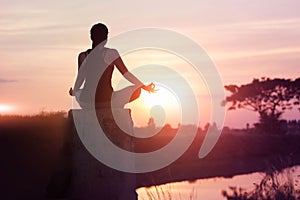 Woman practices yoga and meditates on the nature sunset background