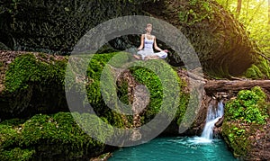 Woman practices yoga in nature, the waterfall. sukhasana pose