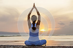 Woman practices yoga at the seashore at sunset on Bali in indonesia