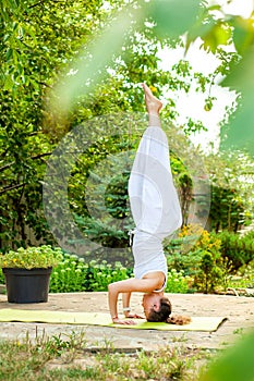 Woman practices yoga in summer garden - Salamba Sirsasana II, Tripod Headstand