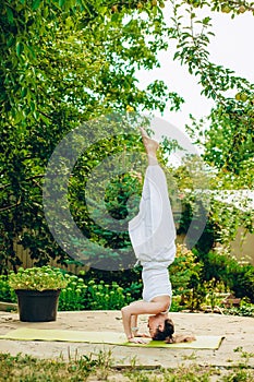 Woman practices yoga in summer garden - Salamba Sirsasana II, Tripod Headstand