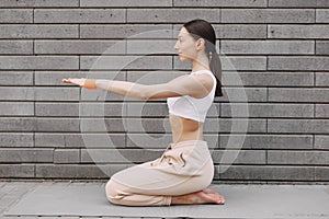 Woman practicing advanced yoga against a dark urban wall
