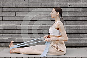 Woman practicing advanced yoga against a dark urban wall