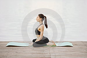 Woman practicing advanced yoga by the water