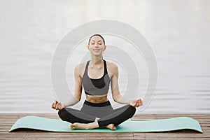 Woman practicing advanced yoga by the water