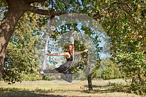Woman practicing antigravity yoga at the tree near the river
