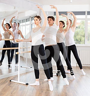 Woman practicing battement tendu at barre at ballet group class photo