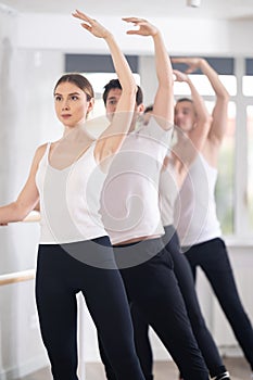 Woman practicing battement tendu at barre at ballet group class photo