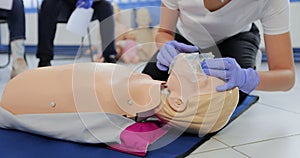 Woman practicing CPR on mannequin at first aid class.