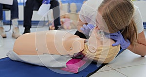 Woman practicing CPR on mannequin at first aid class.