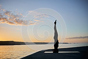 woman practicing a difficult yoga pose during sunset time