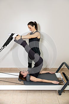 A woman practicing exercises with a pilates personal trainer.