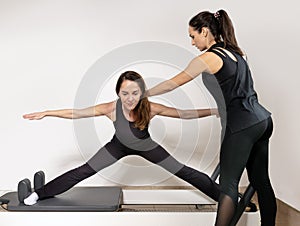 A woman practicing exercises with a pilates personal trainer.