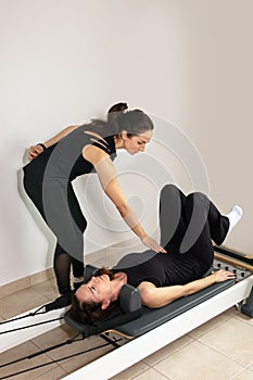 A woman practicing exercises with a pilates personal trainer.