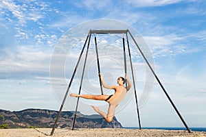 Woman practicing fly dance gravity yoga poses in a hammock outdoors