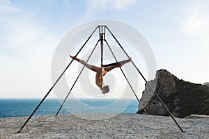 Woman practicing fly dance gravity yoga poses in a hammock outdoors