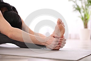 Woman practicing head to knee asana in yoga studio, closeup. Janu Sirsasana pose