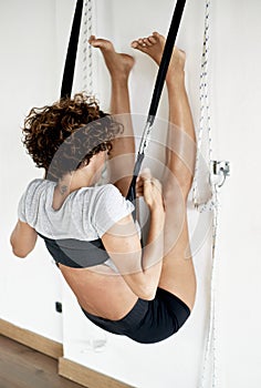 Woman practicing iyengar yoga using wall ropes in studio