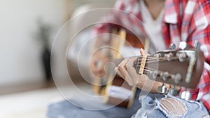 Woman practicing or learning to play guitar and practice using his fingers to hold guitar chords while looking