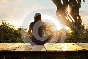 Woman practicing meditation yoga on the nature at sunset