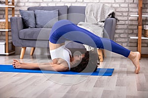 Woman Practicing Plow Pose On Yoga Mat