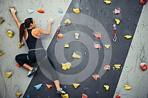 Woman practicing rock climbing on artificial wall indoors. Active lifestyle and bouldering concept.