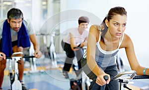 Woman practicing on speed bike at gym. Beautiful woman working out on a stationary bike at the gym.