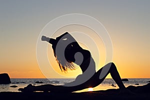 woman practicing stretching at sunset. seaside background, silhouette