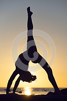 woman practicing stretching at sunset. seaside background, silhouette