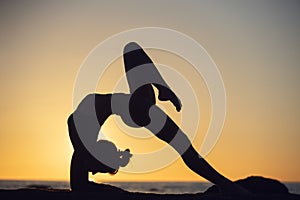 woman practicing stretching at sunset. seaside background, silhouette